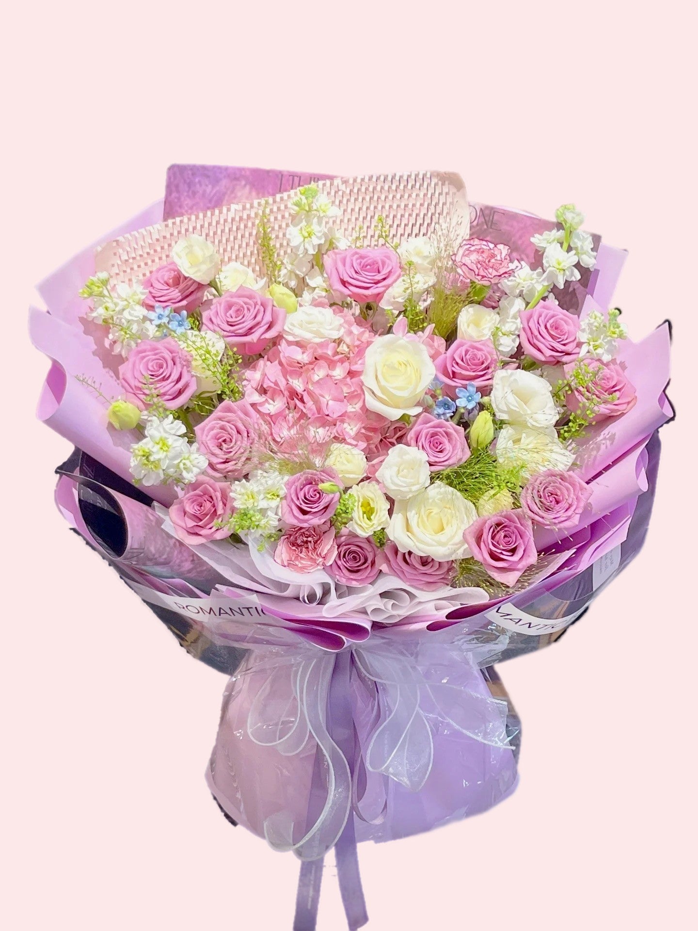 Bouquet of pink and purple roses, pink hydrangeas, white lisianthus, white violets, and blue starflowers