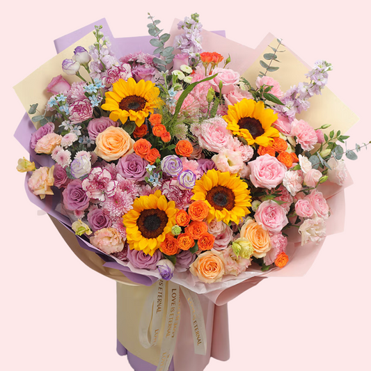 Large 4-stem sunflower with pink, purple, champagne roses, purple carnations, small blue flowers and bubble bouquets